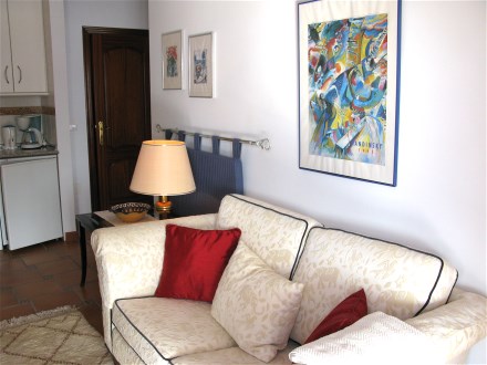 Das Wohnzimmer hat eine helle Couche und eine offene K�pche